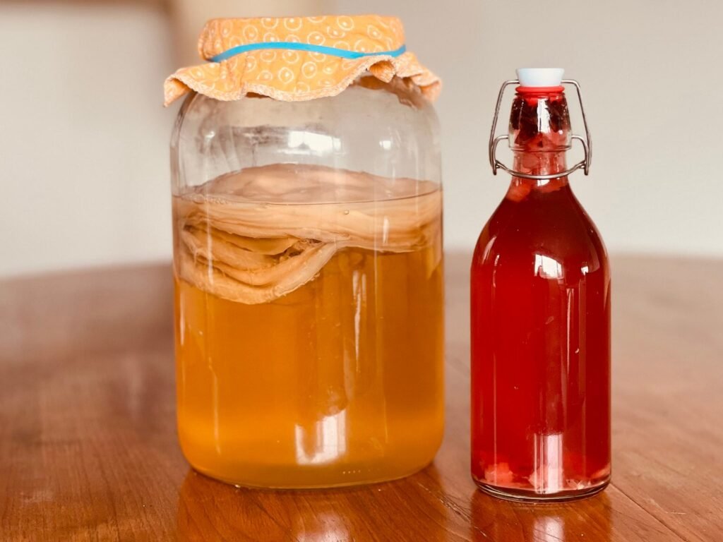 a jar of kombucha brewing and a bottle of finished kombucha